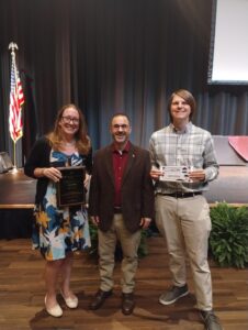 picture of Jenna Hulke holding award, standing next to Charles Criscione and Ryan Manness who is holding a certificate