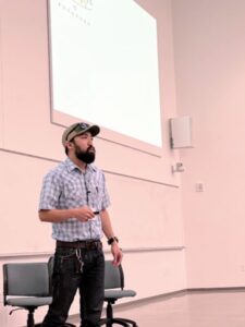 New Directory Photos (51) man in hat and blue checkered shirt presenting