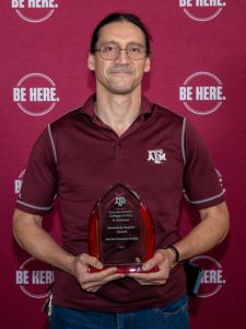 picture of Daniel Paredes-Sabja holding award in front of maroon background