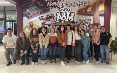 group of people posing next to mural